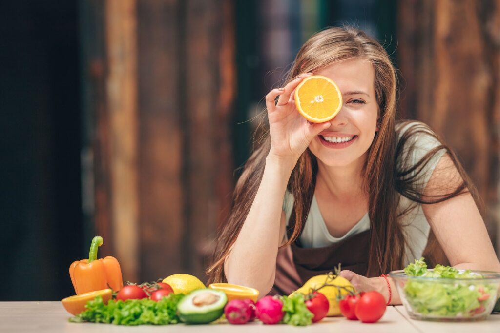 Eine Frau hält eine Orange vor ihr Gesicht