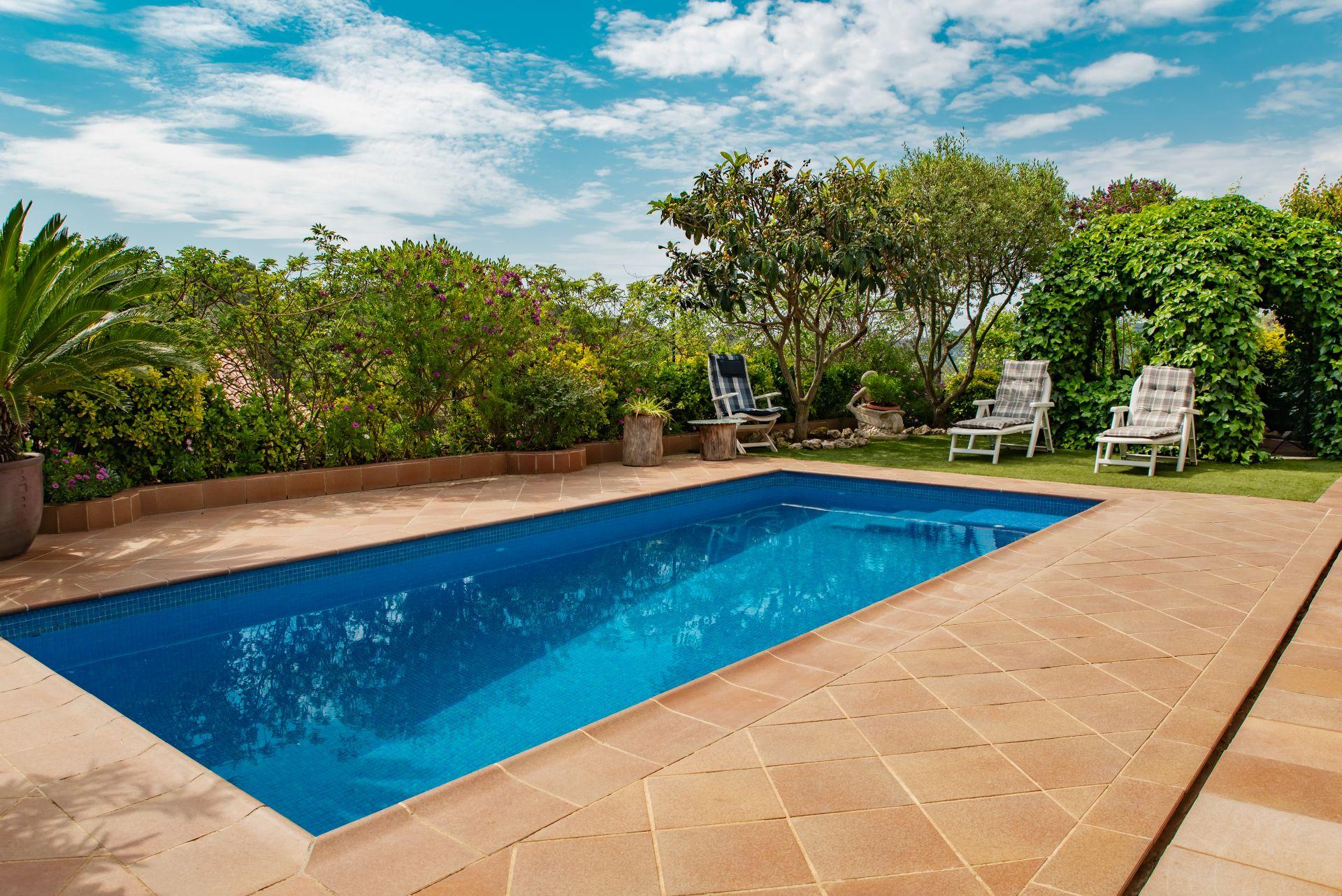 Rechteckiger Pool mit mediterraner Terrasse, Garten und Fliesen bei sonnigem Wetter