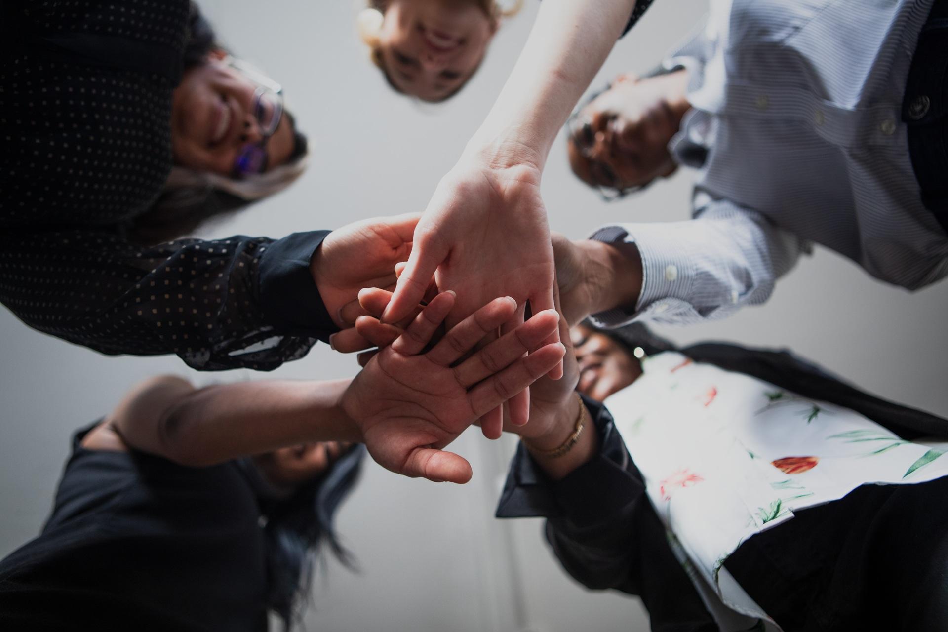 Gruppe legt Hände übereinander | Pflegehilfskraft Ausbildung